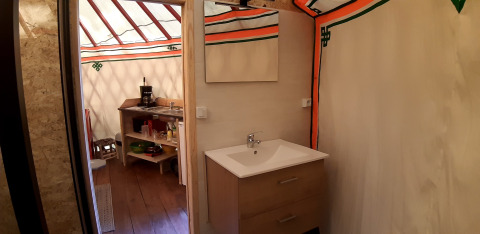 Vista interna di una yurta moderna al Campeggio Ushuaïa Villages Le Viaduc con lavandino e angolo cottura.