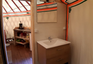 Vista interna di una yurta moderna al Campeggio Ushuaïa Villages Le Viaduc con lavandino e angolo cottura.