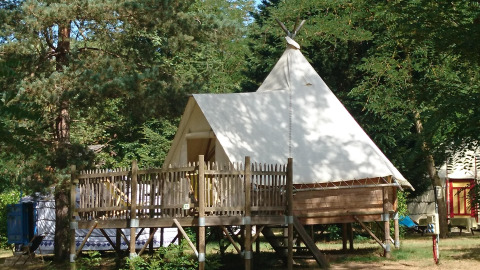 Tipi Lodge al campeggio Ushuaïa Villages Le Viaduc in Francia, tenda rialzata immersa nel verde.
