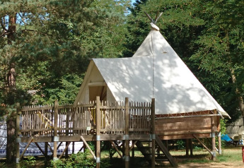 Tipi Lodge at Campsite Ushuaïa Villages Le Viaduc in France, an elevated tent structure in a wooded area.