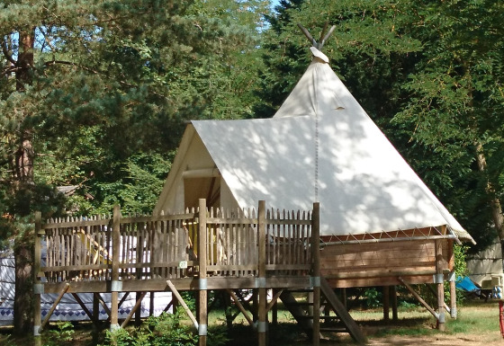 Tipi Lodge al campeggio Ushuaïa Villages Le Viaduc in Francia, tenda rialzata immersa nel verde.
