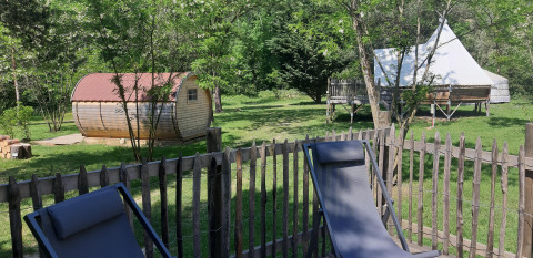 Area esterna rilassante con recinto in legno, sedie a sdraio, baita e tenda tipì al Tipi Lodge in Francia.