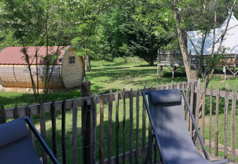 Relaxing outdoor setting with wooden fence, lounge chairs, cabin, and tipi tent at Tipi Lodge in France.