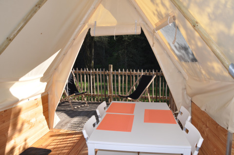 Vista interna dalla Tipi Lodge al Campeggio Ushuaïa Villages Le Viaduc, Francia, con tavolo e terrazza esterna.