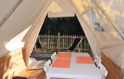 Interior view from Tipi Lodge at Campsite Ushuaïa Villages Le Viaduc, France, with table and outside deck.