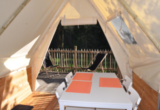 Vista interna dalla Tipi Lodge al Campeggio Ushuaïa Villages Le Viaduc, Francia, con tavolo e terrazza esterna.