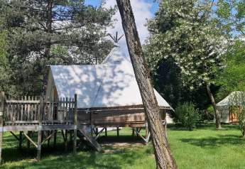 Tipi Lodge at Campsite Ushuaïa Villages Le Viaduc in France, surrounded by lush trees and greenery.