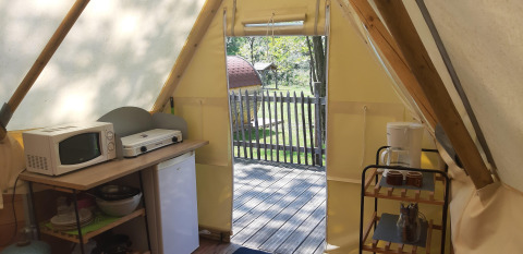Vista interna della Tipi Lodge al Campeggio Ushuaïa Villages Le Viaduc con angolo cucina e terrazza in legno.
