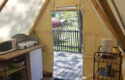 Inside view of Tipi Lodge at Campsite Ushuaïa Villages Le Viaduc, showing kitchen facilities and deck area.