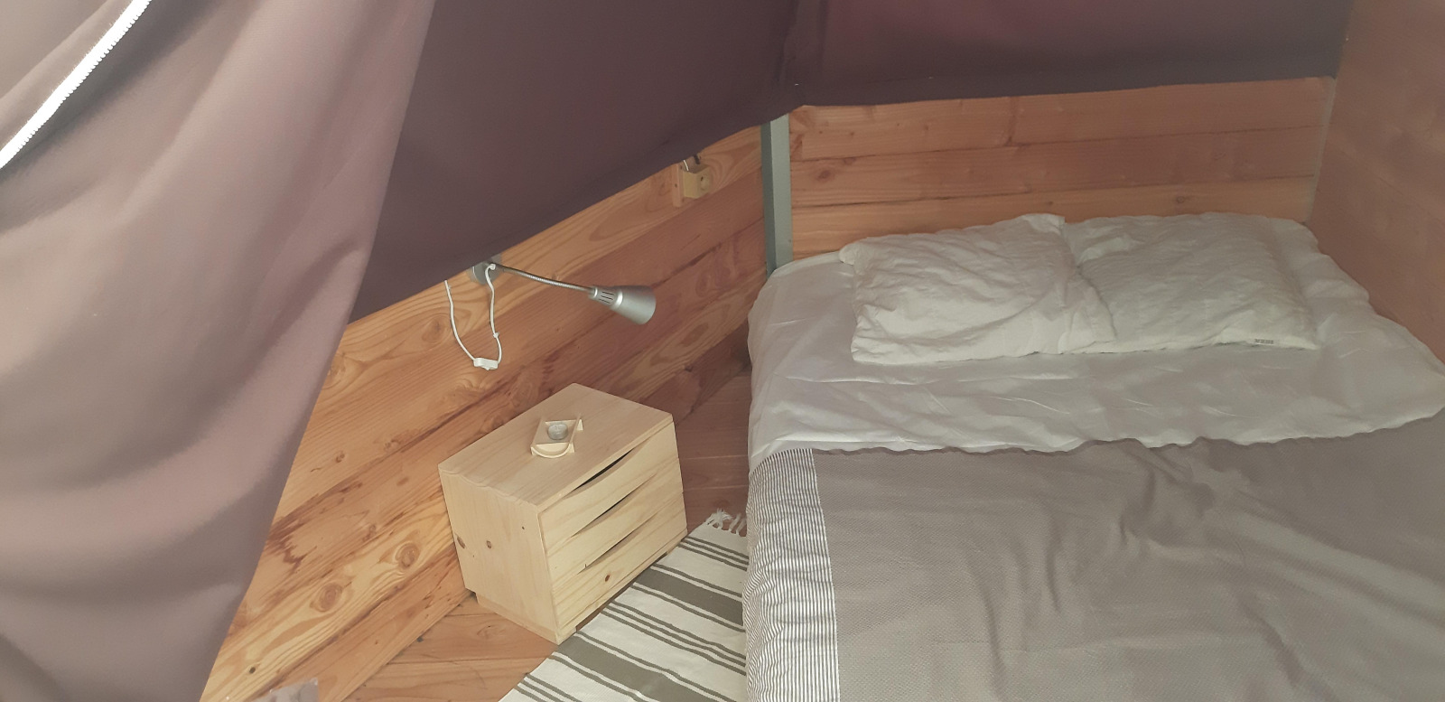 Binnenaanzicht van de Tipi Lodge op Campsite Ushuaïa Villages Le Viaduc met bed en nachtkastje.