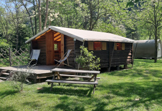 A cozy log cabin with deck and picnic table at Ushuaïa Villages Le Viaduc campsite in France.