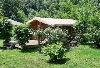 Capanna di legno con veranda coperta circondata dal verde al Campeggio Ushuaïa Villages Le Viaduc in Francia.