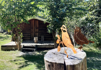 Figure di uccelli in legno su un palo davanti a una baita al campeggio Ushuaïa Villages Le Viaduc in Francia.