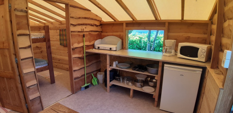 Indvendig af træhytte på Campsite Ushuaïa Villages Le Viaduc med køkkenudstyr og køjesenge.