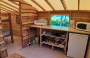 Interior of a log cabin at Campsite Ushuaïa Villages Le Viaduc, featuring kitchen appliances and bunk beds.