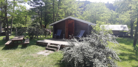 Træhytte på Campsite Ushuaïa Villages Le Viaduc i Frankrig, omgivet af grønne træer og picnicbord.