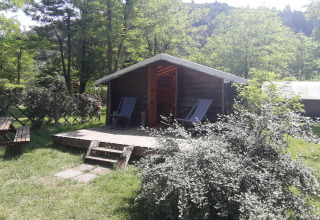 Træhytte på Campsite Ushuaïa Villages Le Viaduc i Frankrig, omgivet af grønne træer og picnicbord.