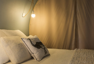 Interior de la tienda safari Coco Sweet en el camping Ushuaïa Villages Le Viaduc, Francia, con cama acogedora.