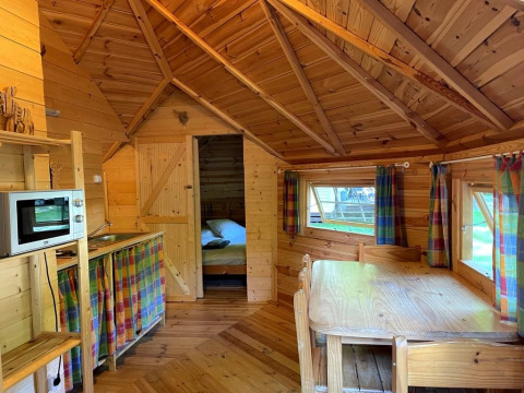 Interior view of a cozy wooden lodge named Finnish kota at Campsite Ushuaïa Villages Le Viaduc in France.