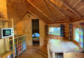 Interior view of a cozy wooden lodge named Finnish kota at Campsite Ushuaïa Villages Le Viaduc in France.