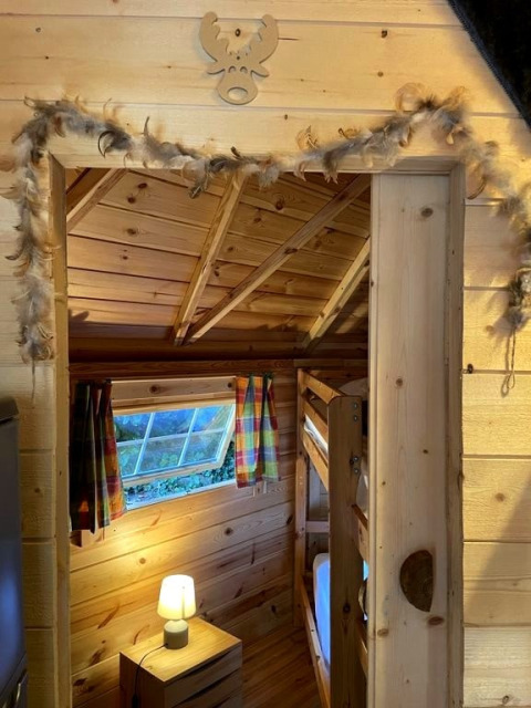 Wooden cabin interior with bunk beds, lamp and colorful curtains at Ushuaïa Villages Le Viaduc campsite.