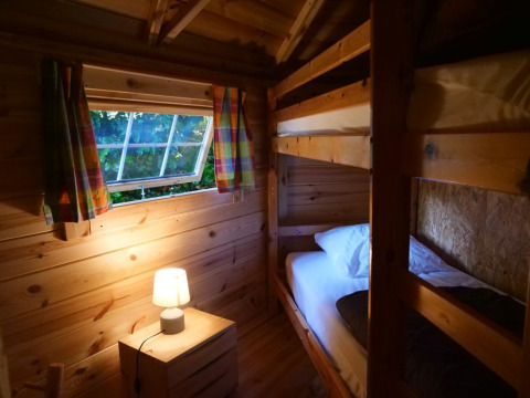 Cozy wooden room with bunk beds and lamp in the Finnish kota at Campsite Ushuaïa Villages Le Viaduc, France.