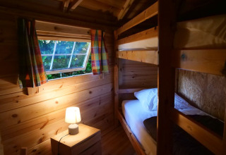 Cozy wooden room with bunk beds and lamp in the Finnish kota at Campsite Ushuaïa Villages Le Viaduc, France.