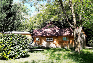 Finnish kota-style wooden lodge surrounded by lush green trees at Campsite Ushuaïa Villages Le Viaduc, France.
