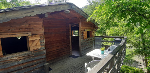 Baumhaus auf einer Holzterrasse mit Sitzbereich und Blick ins Grüne im Ushuaïa Villages Le Viaduc Campingplatz in Frankreich.