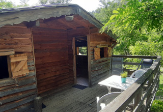 Cabane en bois perchée avec terrasse et coin repas, entourée de verdure au Ushuaïa Villages Le Viaduc en France.
