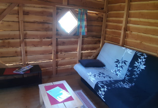 Intérieur d’une cabane dans les arbres au Ushuaïa Villages Le Viaduc, France, avec canapé et murs en bois.