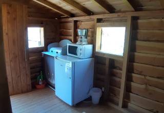 Coin d'une cabane dans les arbres au Camping Ushuaïa Villages Le Viaduc, France, avec frigo et micro-ondes.