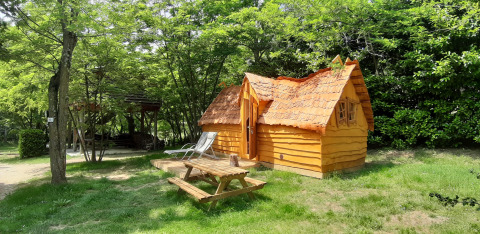 Lille træhus kaldet Magic hut på Campsite Ushuaïa Villages Le Viaduc i Frankrig, omgivet af grønne træer.