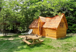 Lille træhus kaldet Magic hut på Campsite Ushuaïa Villages Le Viaduc i Frankrig, omgivet af grønne træer.