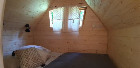 Cozy bedroom with wooden walls in the Magic Hut at Campsite Ushuaïa Villages Le Viaduc in France.