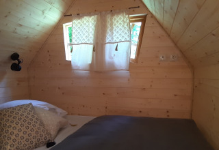 Cozy bedroom with wooden walls in the Magic Hut at Campsite Ushuaïa Villages Le Viaduc in France.