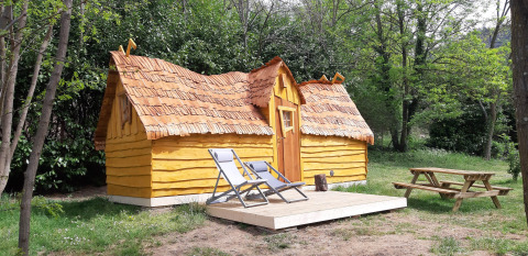 Magic hut at Campsite Ushuaïa Villages Le Viaduc in France, featuring a wooden terrace and lounge chairs.