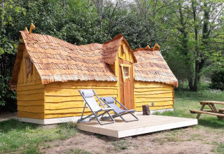 Magic hut at Campsite Ushuaïa Villages Le Viaduc in France, featuring a wooden terrace and lounge chairs.