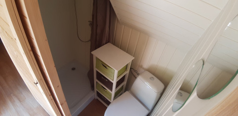 Small bathroom at Magic Hut, Ushuaïa Villages Le Viaduc, France, with shower, toilet, and storage bins.