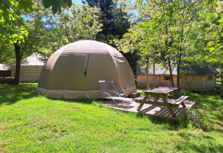 Tienda cúpula Wigwam con mesa de picnic en Campsite Ushuaïa Villages Le Viaduc, rodeada de árboles y césped verde.