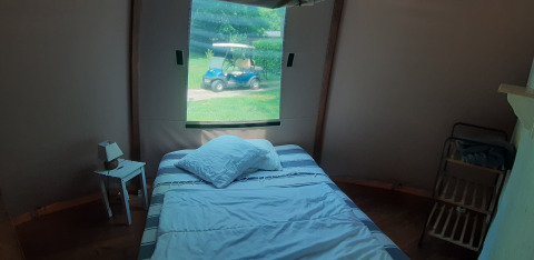 Bedroom in Wigwam dome at Ushuaïa Villages Le Viaduc with bed, nightstand, and window overlooking golf cart.