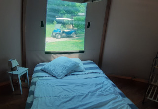 Bedroom in Wigwam dome at Ushuaïa Villages Le Viaduc with bed, nightstand, and window overlooking golf cart.
