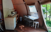 Binnenzicht van de Wigwam-koepel bij Ushuaïa Villages Le Viaduc, Frankrijk, met tafel, stoelen en kitchenette.