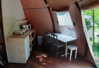 Intérieur d’un dôme Wigwam au Camping Ushuaïa Villages Le Viaduc en France, avec table, chaises et kitchenette.