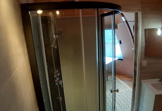 Salle de bain avec douche et lavabo dans le Wigwam Dome au Camping Ushuaïa Villages Le Viaduc, France.