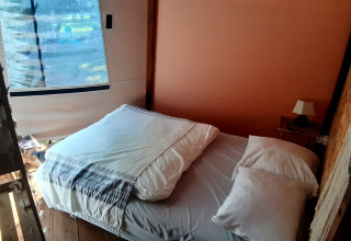 Acogedora zona de descanso en el domo Wigwam del camping Ushuaïa Villages Le Viaduc, Francia, con cama cómoda.