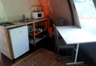 Køkkenområde i Wigwam dome på Campsite Ushuaïa Villages Le Viaduc, med bord, stole og vindue.