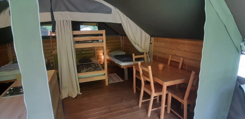 Inde i Kibo-safari teltet på Ushuaïa Villages Le Viaduc, med køjeseng, spisebord og trævægge.