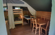 Intérieur de la tente safari Kibo à Ushuaïa Villages Le Viaduc, avec lits superposés et table en bois.