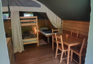 Inde i Kibo-safari teltet på Ushuaïa Villages Le Viaduc, med køjeseng, spisebord og trævægge.